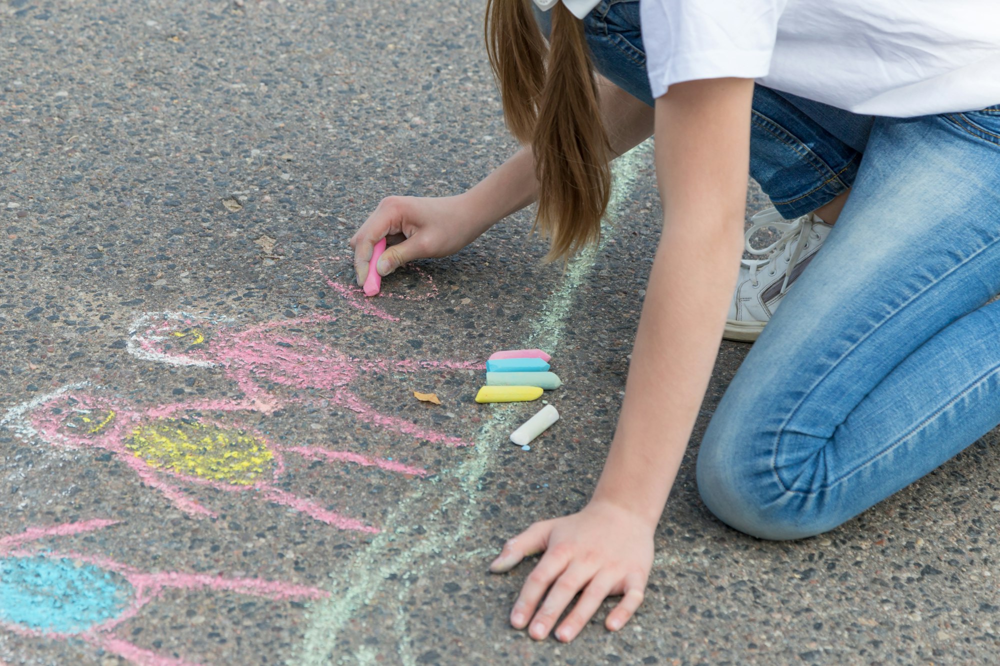 Children's hand draws with crayons on the asphalt